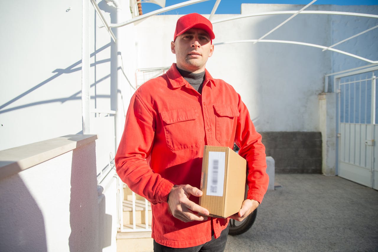 Man in Red Jacket Holding Brown Cardboard Box